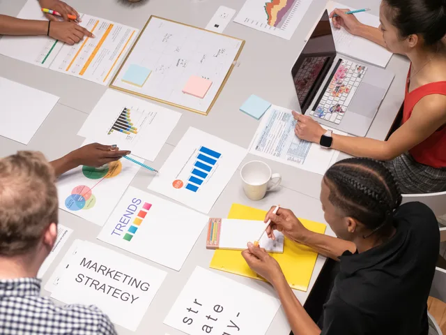 Overhead shot of diverse team analyzing marketing strategies with charts and graphs. Varumärkesmätning: nyckeltal och metoder för att följa varumärkets styrka